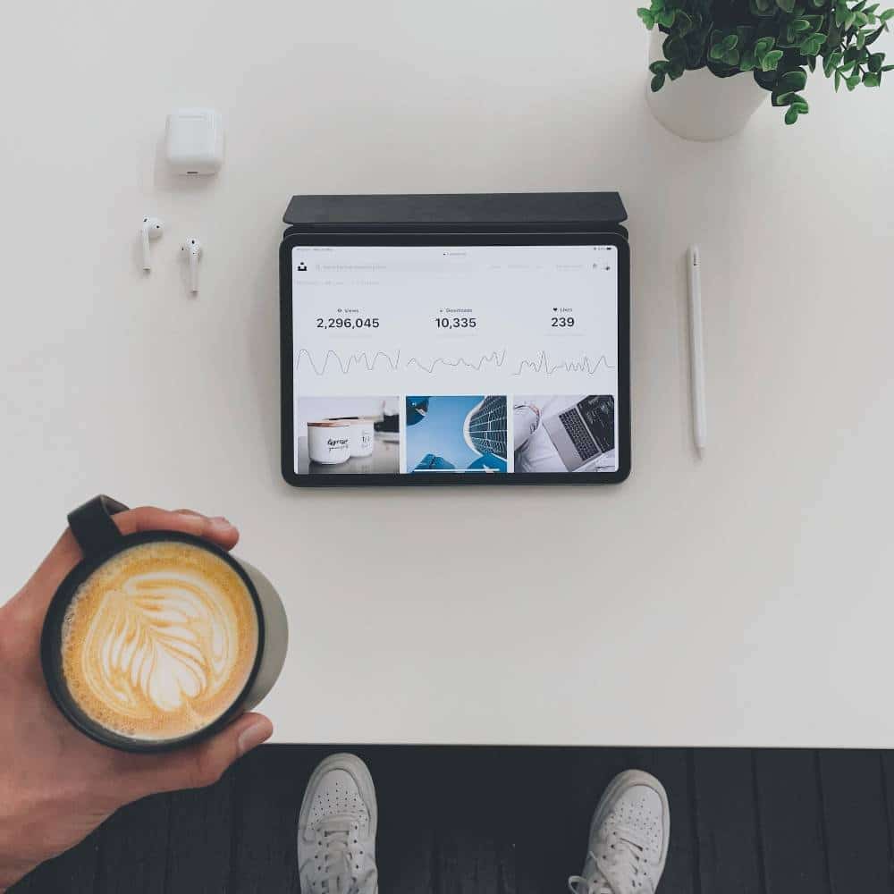 a cup of coffee with analytics of digital marketing open on the screen of an ipad