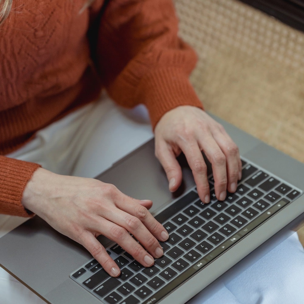 close up of hands using a laptop and typing on the keyboard