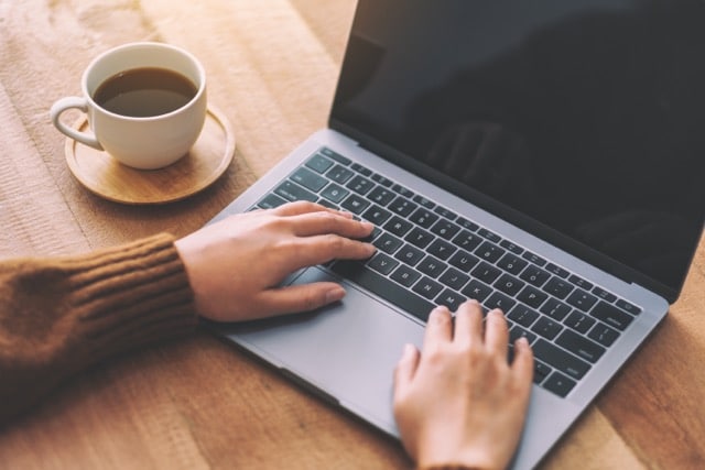 Closeup image of woman's hands using and typing on laptop computer keyboard